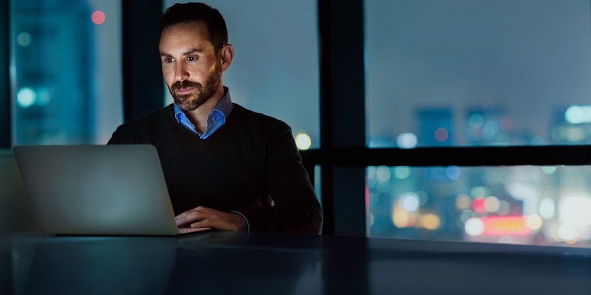 Ein IT-Mitarbeiter sitzt an seinem Schreibtisch im Büro und arbeitet in OpenTelemetry.